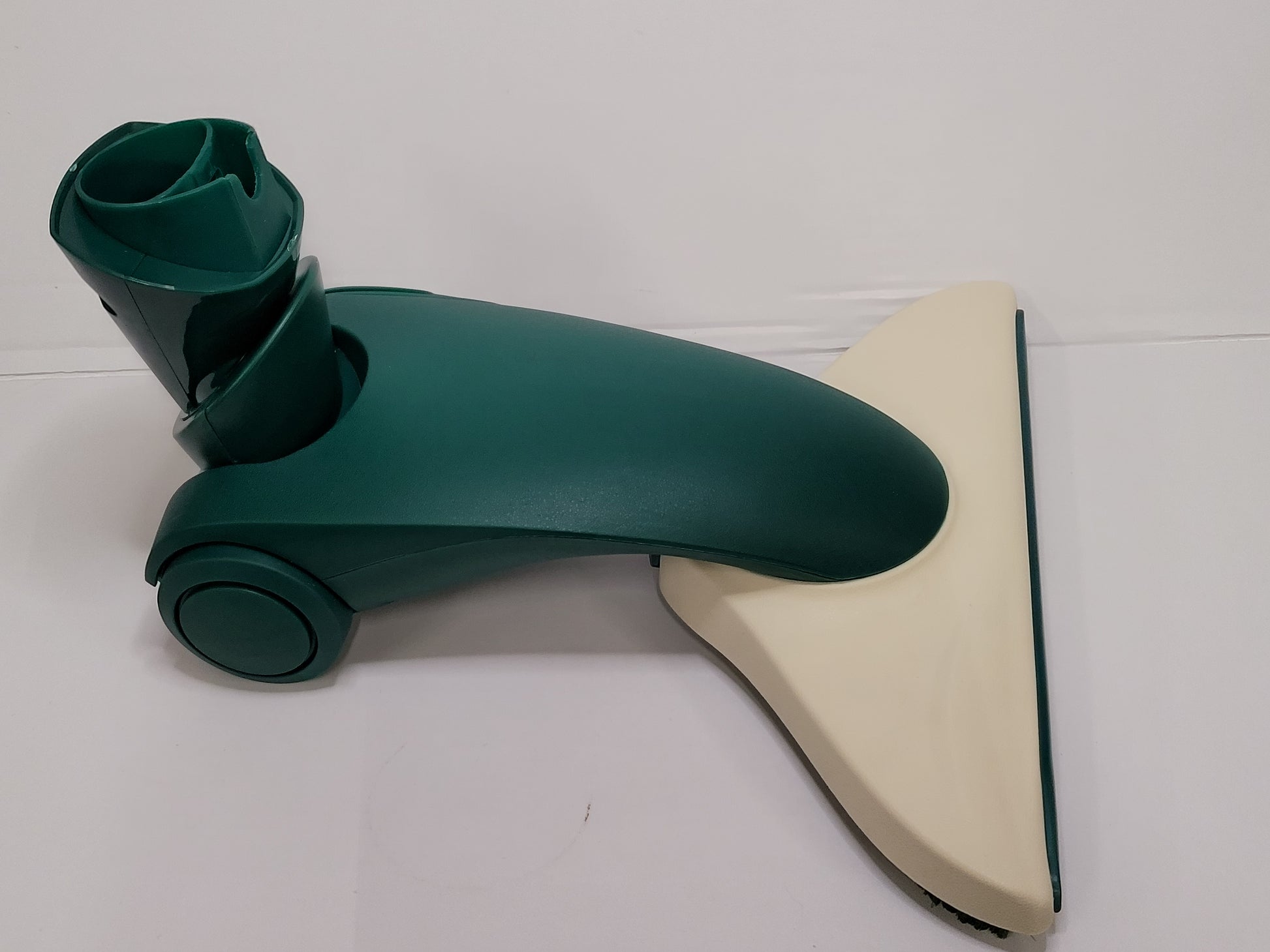 Eine Staubsauger-Bodendüse mit einem dunkelgrünen, gebogenen Körper und einer breiten, cremefarbenen, dreieckigen Basis auf weißem Hintergrund. Die immer-saugut Bodendüse kompatibel HD 35 verfügt über einen runden Anschluss zur Befestigung des Staubsaugerschlauchs.