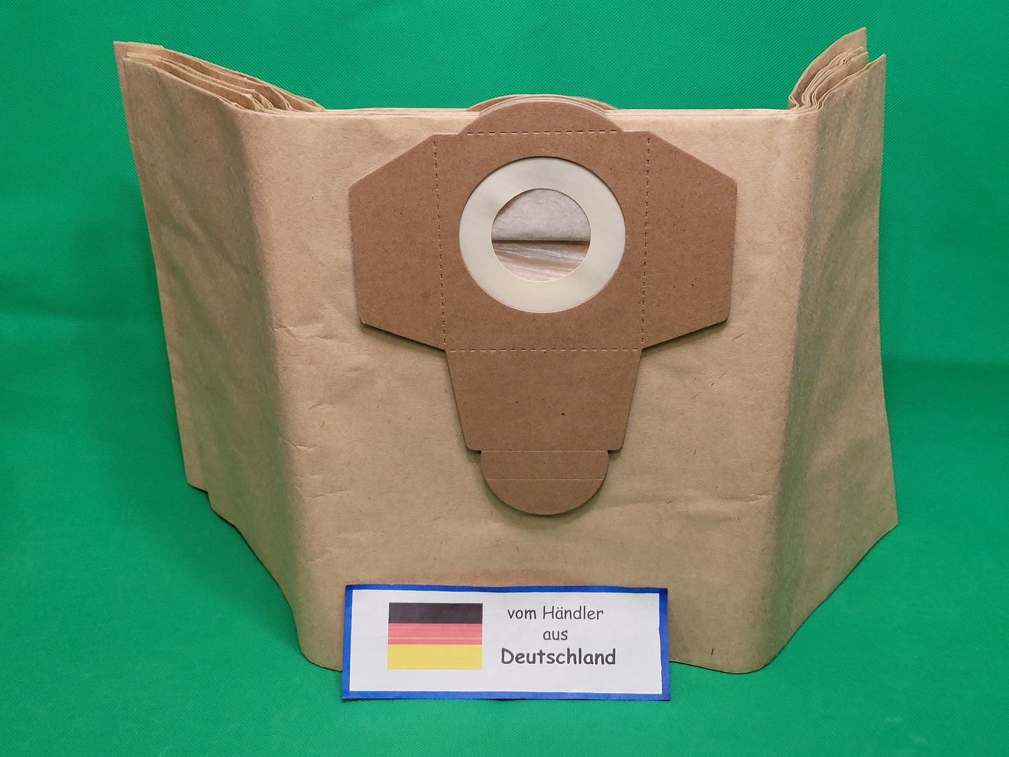 Ein brauner Staubsaugerbeutel der Marke Unbekannt/Sonstige mit Kartonkragen steht auf grünem Hintergrund. Davor liegt ein Etikett mit deutscher Flagge und "vom Händler aus Deutschland". Passend für Einhell 20 Liter, 30 Beutel pro Packung.