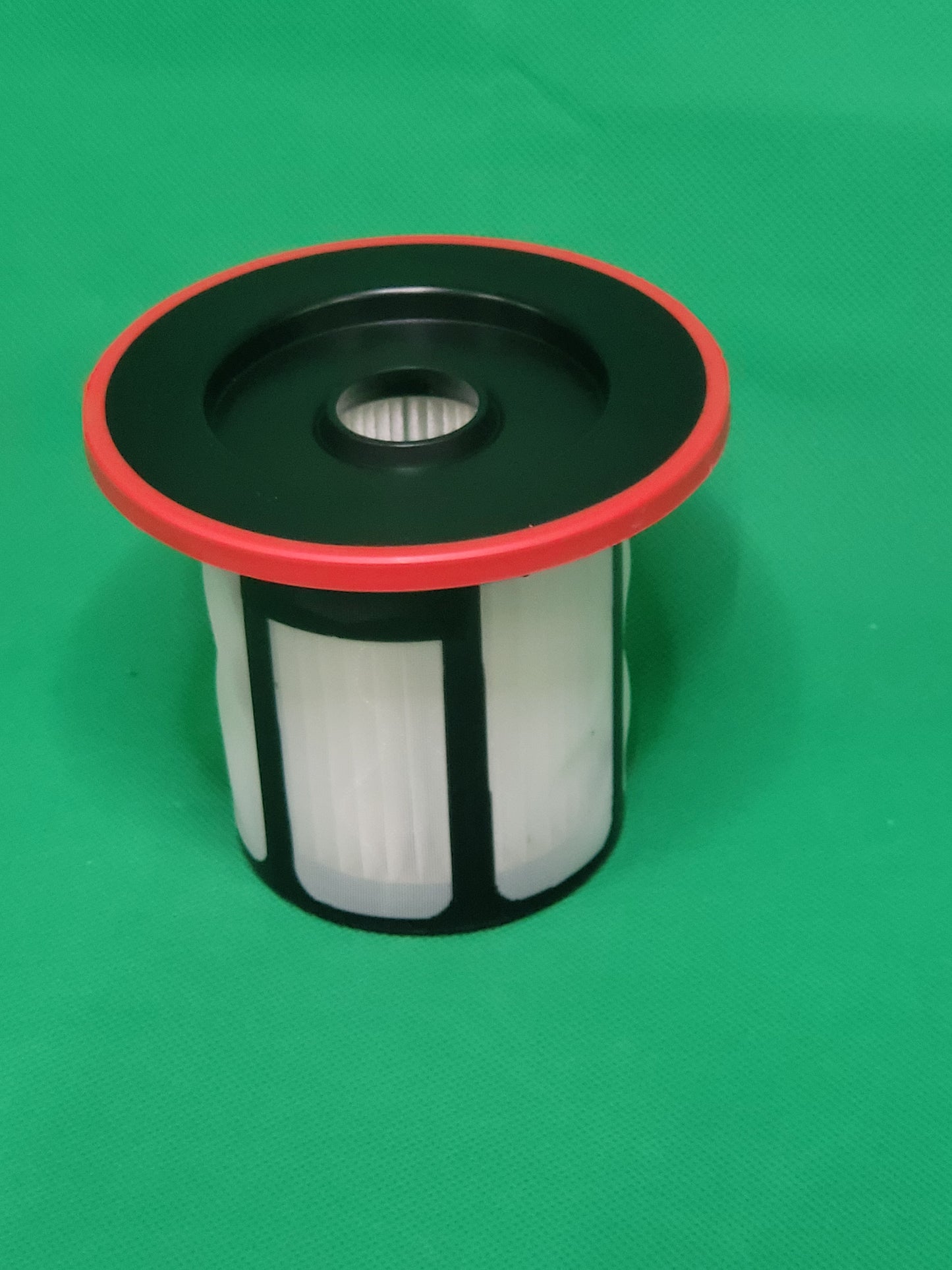 Ein unbenutzter ALMEc Supplies Filter kompatibel mit Bosch Serie 6, BCS6, BSS6, BKS6, BBS6, BLS6, 12033215 hat einen schwarzen Kunststoffdeckel, einen roten Rand und weiße Falten und sitzt aufrecht auf einer grün strukturierten Oberfläche.