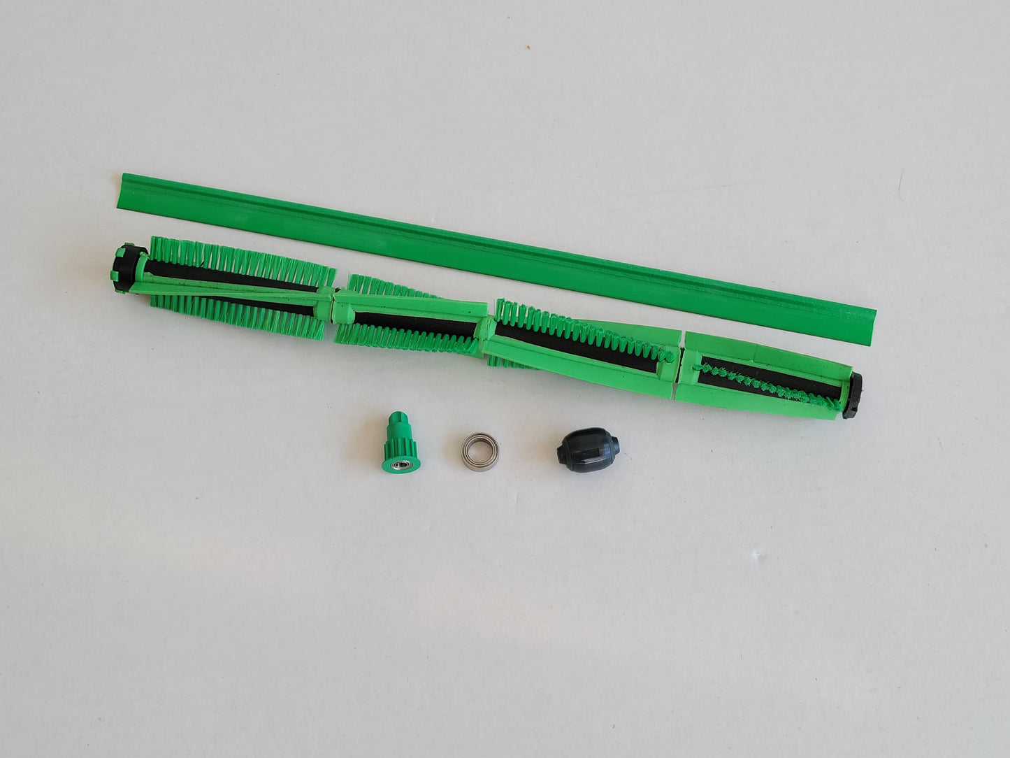 Ein zerlegtes RMO Bürste Ritzel Lager Dichtlippe Rad Set, kompatibel mit Vorwerk EB 400, mit grüner Bürste, Streifenabdeckung, Kappe, Metallring und Endstück ist auf einer weißen Fläche ausgestellt.