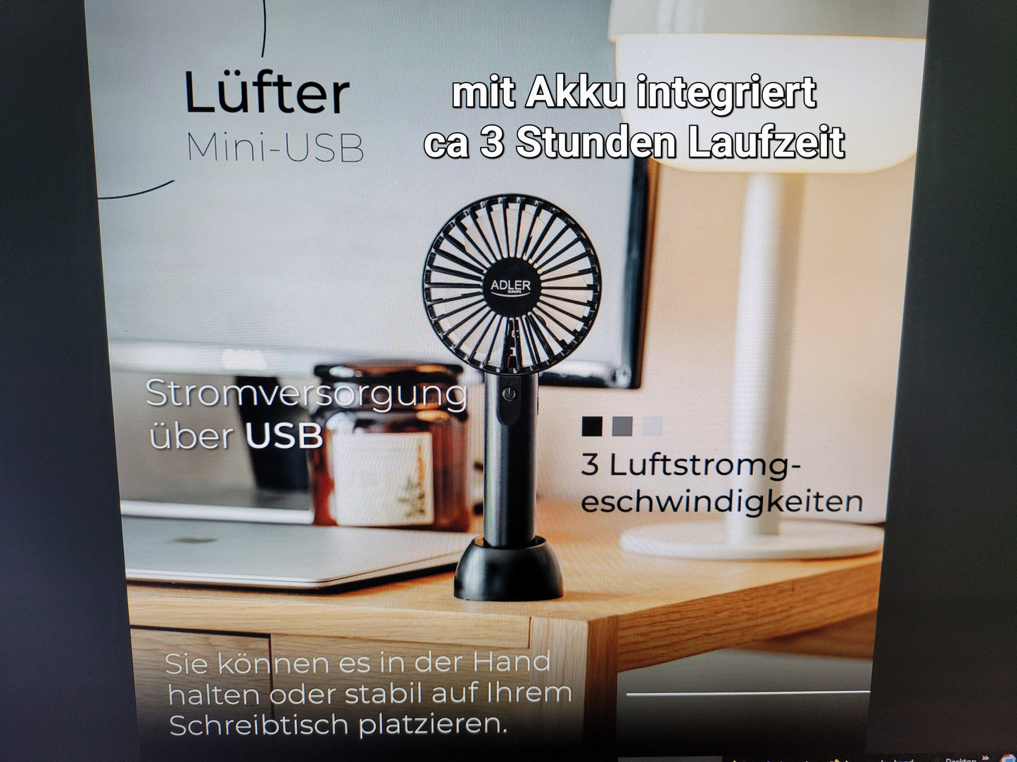 Ein kompakter schwarzer Mini-Handventilator AD 7338 von immer-saugut steht auf einem Schreibtisch. Ein deutscher Text weist auf einen integrierten Akku (ca. 3 Stunden Laufzeit), die Stromversorgung über USB-Kabel, 3 Lüfterstufen sowie den flexiblen Einsatz als tragbarer oder Tischventilator hin.
