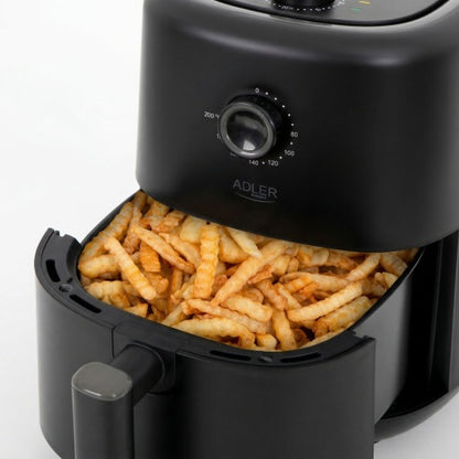 Eine schwarze Heißluftfritteuse der Adler Europe GmbH mit 3 Litern Fassungsvermögen und 2200 Watt (Modell AD 6310) sowie einer offenen Schublade ist mit fertig zubereiteten, gewellten Pommes frites gefüllt. Der Temperaturregler des Geräts (80–200 °C) ist sichtbar, und die Fritteuse steht auf einer weißen Fläche. Die goldbraunen, knusprigen Pommes frites zeigen perfekt, wie das Frittieren ohne Fett in dieser Heißluftfritteuse köstliche und gesündere Ergebnisse liefert.