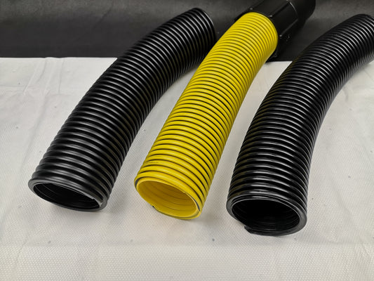 Auf einer weißen Fläche sind drei zylindrische, flexible Wellschläuche abgebildet. Der mittlere Schlauch ist der gelbe, geriffelte immersaugende Saugschlauch Meterware 51 mm, während der linke und rechte Schlauch schwarz sind.