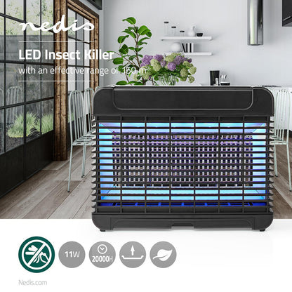 Auf einer Küchenarbeitsplatte steht ein eleganter schwarzer Insektenvernichter „Fliegenfalle 150 m²“ der Nedis GmbH mit blauen UV-A-LED-Leuchten. Hinter der LED-Lampe sind Blumen, Zitronen und andere Küchenutensilien zu sehen. Symbole am unteren Rand zeigen an, dass das Gerät eine Leistungsaufnahme von 11 W hat, eine Lebensdauer von 20.000 Stunden aufweist und eine Fläche von bis zu 150 m² abdeckt.