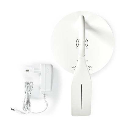 Eine moderne, weiße, dimmbare LED-Tischleuchte bzw. Schreibtischlampe von „immer-saugut“ mit schlankem, flachem Sockel, Touch-Bedienung und einem Symbol für kabelloses Laden steht neben einem weißen Netzteil mit Spiralkabel – beides auf weißem Hintergrund arrangiert. Diese stilvolle LED-Leuchte vereint elegantes Design und Funktionalität: Dank der integrierten Qi-Ladefunktion lassen sich Ihre Geräte bequem kabellos aufladen.