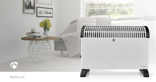Ein modernes Wohnzimmer verfügt im Vordergrund über ein weißes Immersaugut-Konvektor-Heizgerät von Nedis mit Drehfunktion, verstellbarem Thermostat und 3 Wärmeeinstellungen, das 2000 Watt Leistung liefert. Der Raum umfasst eine weiße Couch mit einer grau-