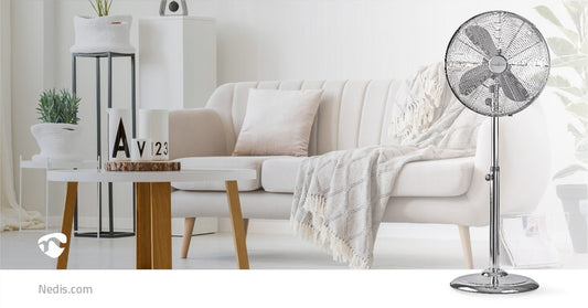 Ein modernes Wohnzimmer verfügt über ein weißes Sofa mit einer beigen Überwurfdecke, einen runden weißen Couchtisch mit einer Pflanze und Dekoartikeln und einen Nedis - Standventilator von Nedis GmbH mit 3 Leistungsstufen, einfacher Bedienung, Schwingungs