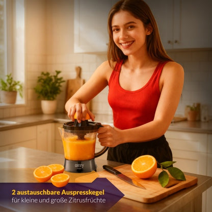Eine junge Frau in einem roten Tanktop benutzt in einer hellen Küche die „Elektrische Zitruspresse Entsafter CR 4008“ der Adler Europe GmbH. Auf der Arbeitsplatte liegen halbierte Orangen und frisch gepresster Orangensaft, bereit für den frisch gepressten Saft. Der Text auf Deutsch lautet: „2 austauschbare Auspresskegel für kleine und große Zitrusfrüchte.“.